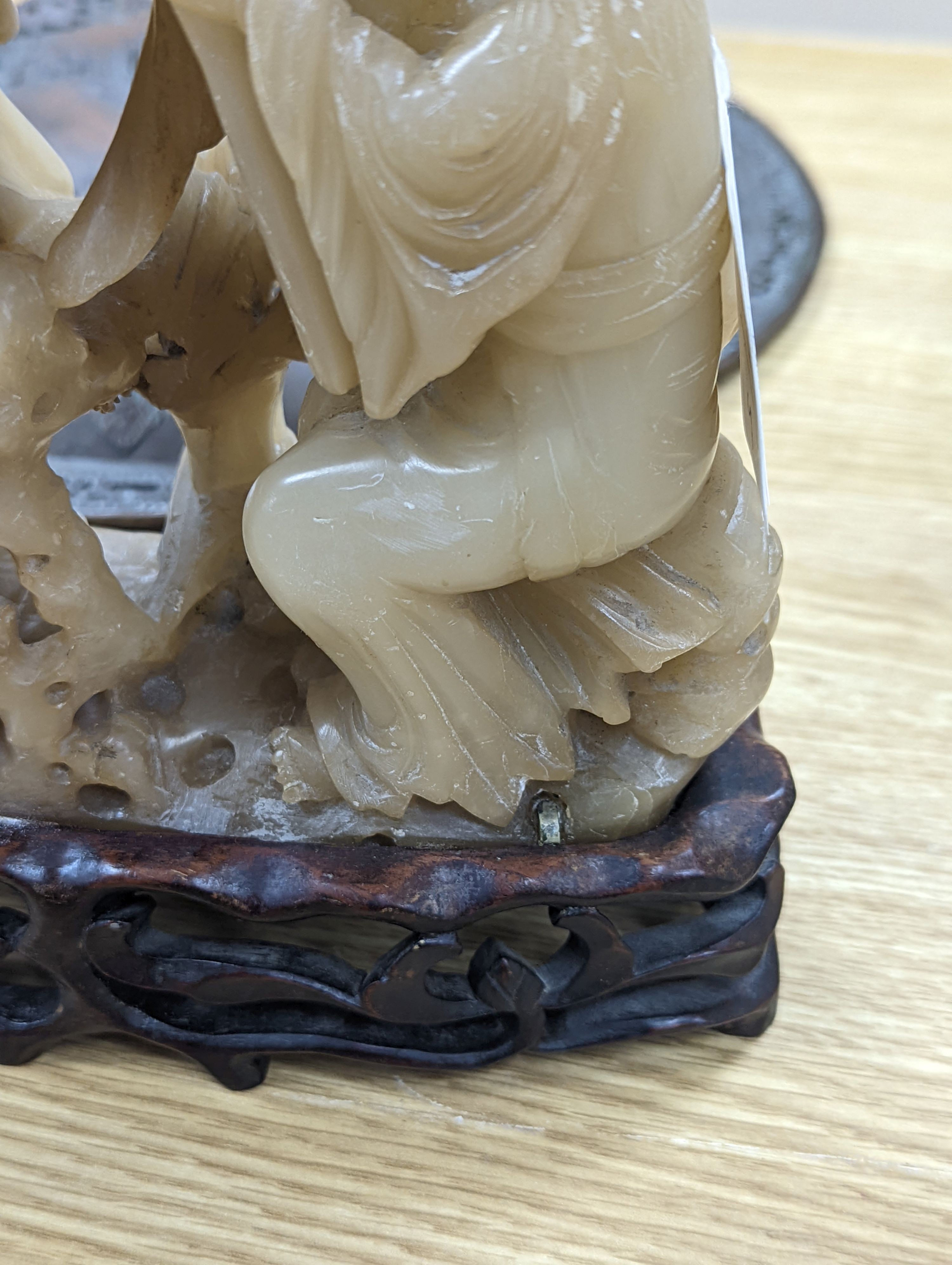 A Chinese soapstone carving of two ladies, wood stand, early 20th century, 36 cms high.